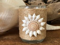 a close up of a candle on a table with shells and other items in the background