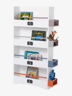 a white book shelf filled with books on top of each other and two bins