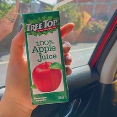 a person holding up a carton of apple juice in their hand while sitting in a car