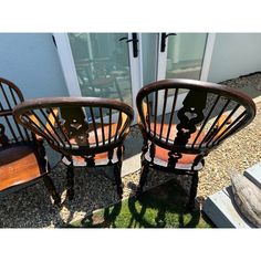 two wooden chairs sitting next to each other in front of a building with glass doors