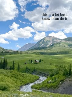 there is a green field with mountains in the background and a river running through it