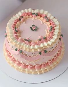 a three tiered cake with pink and white frosting on a platter in the shape of a heart