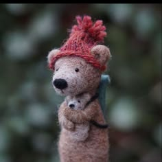 a small teddy bear with a red hat on it's head is holding something