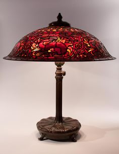 a lamp that is sitting on top of a table with a red shade over it