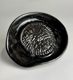 a black plate with an intricate design on the rim and bottom, sitting on a white surface