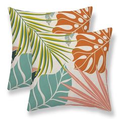 two pillows with tropical leaves on them, one in orange and the other in green