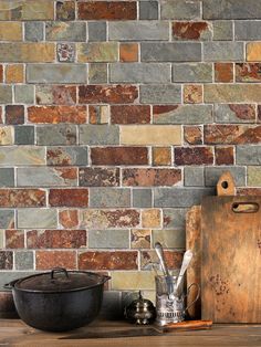 a wooden cutting board sitting on top of a table next to a wall covered in bricks