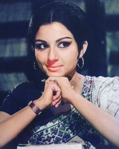 a woman sitting at a table with her hands folded