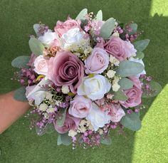 a bridal bouquet with pink and white flowers is held by someone's hand