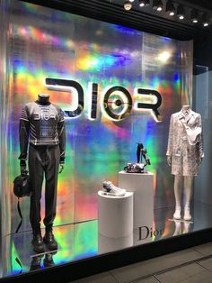 a display case with two mannequins in front of it and the word dior on the wall