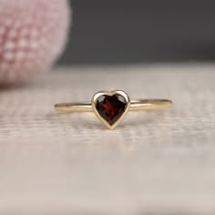 Ashly Follow your heart and it will lead you to our gold rings. This red heart ring has a beautiful heart shape cut and would make the perfect gift for her. Available in Yellow Gold, White Gold, and Rose Gold. - Handmade - Solid Gold- Natural Garnet- Total Garnet Carat Weight: .48 ctw- Bezel Setting Size: 7.5 mm- Ring Band: 1.4 mm All pieces come beautifully boxed in suede pouches you can always use (which really comes in handy when traveling!) Dainty Garnet Ring, Garnet Heart Ring, Heart Gem Ring, Vintage Promise Rings, Red Heart Ring, Heart Ring Gold, Promise Ring Gold, Gold Garnet Ring, Golden Rings