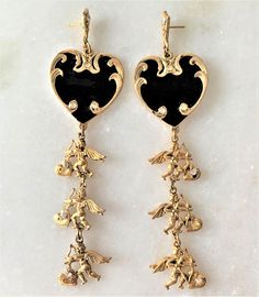 "Antique Gold Tone Hearts & Cupids Drop Pierced Earrings Black Enamel Hand Painted Hearts Hand Set with Faceted Crystal Stones Double Sided Cupids with Wings, Hearts and Bow & Arrows Dangle From the Enamel Hearts Cupids Hearts Hand Set with Faceted Crystal Stones Cupid Dangles are Double Sided with Crystals Hand Set on Both Sides of Hearts Each Earring Hand Set with 10 Crystals Earrings Measure 4 1/2\" Long Black Enamel Hearts Measure 1 1/4\" in Diameter Surgical Steel Posts Silver Tone Valentine's Day Enamel Dangle Earrings, Gold Heart Jewelry With Black Enamel, Elegant Heart-shaped Enamel Earrings, Black Enamel Dangle Earrings For Gift, Gold Enamel Heart Charm Earrings, Gold Enamel Heart Earrings, Pierced Enamel Earrings For Anniversary, Gold Enamel Heart Earrings For Valentine's Day, Gift Black Enamel Dangle Earrings