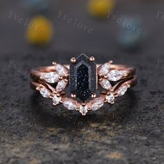 a black diamond ring on top of a stone surface with gold accents and diamonds around the band