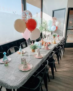 a table set up for a birthday party with balloons and hats on the top tables