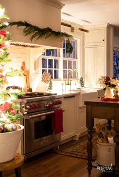 a christmas tree is in the middle of a kitchen with white cabinets and an oven