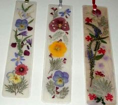 three bookmarks with flowers on them hanging from strings