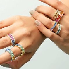 two women's hands with different colored rings on their fingers, both holding each other