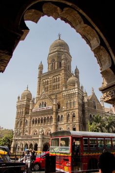 a red bus is parked in front of a large building