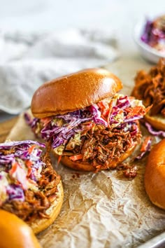 a pulled pork sandwich with coleslaw and slaw on a piece of parchment paper