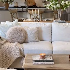 a living room filled with white couches and lots of pillows on top of it