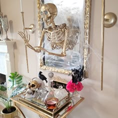 a table with a skeleton on it in front of a mirror and candlesticks