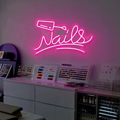 a pink neon sign that says nails on the side of a wall in a room