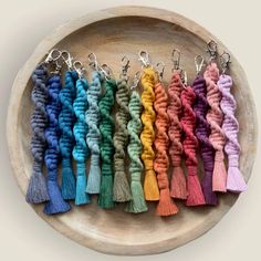 a bunch of different colored tassels are on a wooden tray with metal hooks