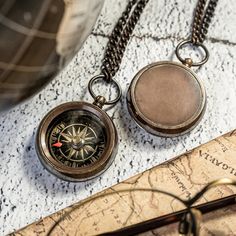 two antique compasses sitting on top of a map next to a pair of glasses