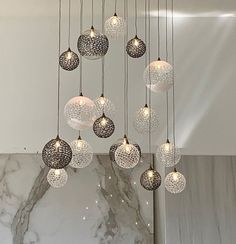 a chandelier made out of glass balls hanging from a marble slab with white walls