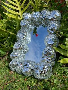 a mirror sitting in the grass near some plants