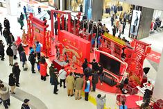 a group of people standing in front of a red display case at a shopping mall