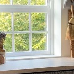 a window sill with vases, broom and other items sitting on the windowsill