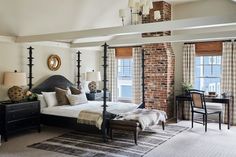 a bedroom with four poster bed and brick wall