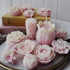 some pink candles are sitting on a plate next to books and other items that look like flowers