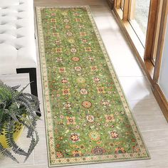 a large green rug in the middle of a living room with a plant on the floor