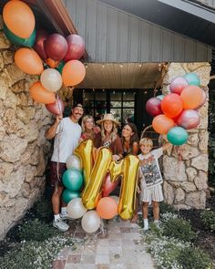 a group of people standing in front of a building with balloons and letters on it