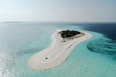 an island in the middle of blue water with white sand on it's sides