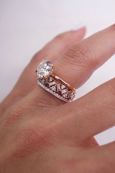 a woman's hand with a diamond ring on top of her wedding band and an engagement ring in the middle