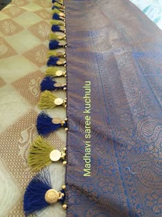 blue and yellow tassels are on the edge of a table with gold accents