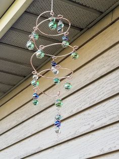 a wind chime hanging from the side of a house with beads and chains attached to it