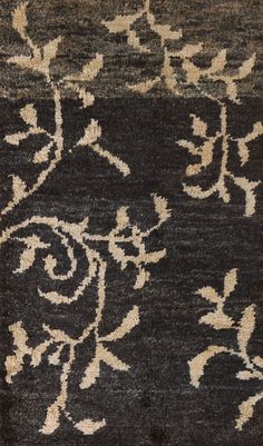 a black and beige area rug with white flowers on the top, in front of a dark background