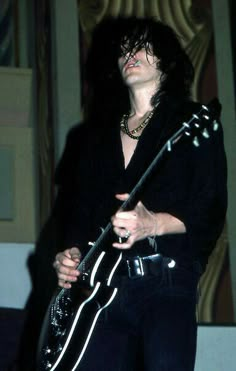 a man with black hair holding a guitar