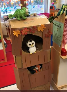 an owl in a cardboard box with leaves on the top and another stuffed animal inside