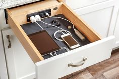 an open drawer in a kitchen with electronics and cords plugged into the side drawers