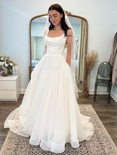 a woman standing in front of a mirror wearing a wedding dress