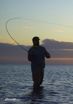 a man standing in the water while holding a fishing rod