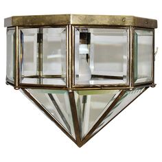 a light that is on the side of a wall mounted fixture with glass panels and gold trimmings