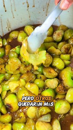 a pot filled with cooked brussel sprouts being stirred by a spatula