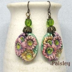 "A bouquet of colorful Gerbera daisies for your ears, these boho dangle earrings feature hand-painted polymer clay charms.  The charms are accented with antiqued brass bead caps and green glass beads on antiqued brass wire. The earrings are about 2.5 inches (6.35 cm) long and the flower charms are about 1 inches (2.5 cm) wide.  The earrings dangle on niobium ear wires. These art jewelry earrings are light weight and comfortable to wear. However, I do not recommend you wear these, or any art jewelry, to sleep, while swimming, etc. Jewelry is inherently fragile and requires special care. In the case of these earrings, that care includes wiping gently with a soft lint-free cloth as needed to clean. Do not use polishing cloths, detergent, or sonic cleaners. For more original earring creations Art Jewelry Earrings, Gerbera Daisies, Dangle Earrings Boho, Gerbera Daisy, Polymer Clay Charms, Clay Charms, Silver Spring, Polymer Clay Beads, Boho Art