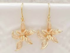 "These are pair of sophisticated and lovely orchid earrings. The beautiful shinning golden plated flower are enhanced with brushed stroke petals. They hang underneath golden plated French ear wires. The earrings measure approximately (32mm) 1.3 inches from the top of the ear wires to the bottom of the flowers. They are perfect for many occasion and everyday wear. They are also a great idea for gift giving and as a little treat for yourself. Your earrings will present in a gift box and tied with Cheap Gold Earrings With Birth Flower Detail, Elegant Gold Earrings With Flower Decoration, Delicate Gold Flower Charm Earrings, Delicate Gold Flower Earrings With Charm, Gold Delicate Flower Earrings, Delicate Gold Flower Earrings For Formal Events, Delicate Gold Flower Earrings For Formal Occasions, Gold Flower Earrings With Ear Wire For Formal Occasions, Dainty Gold Flower Earrings For Anniversary